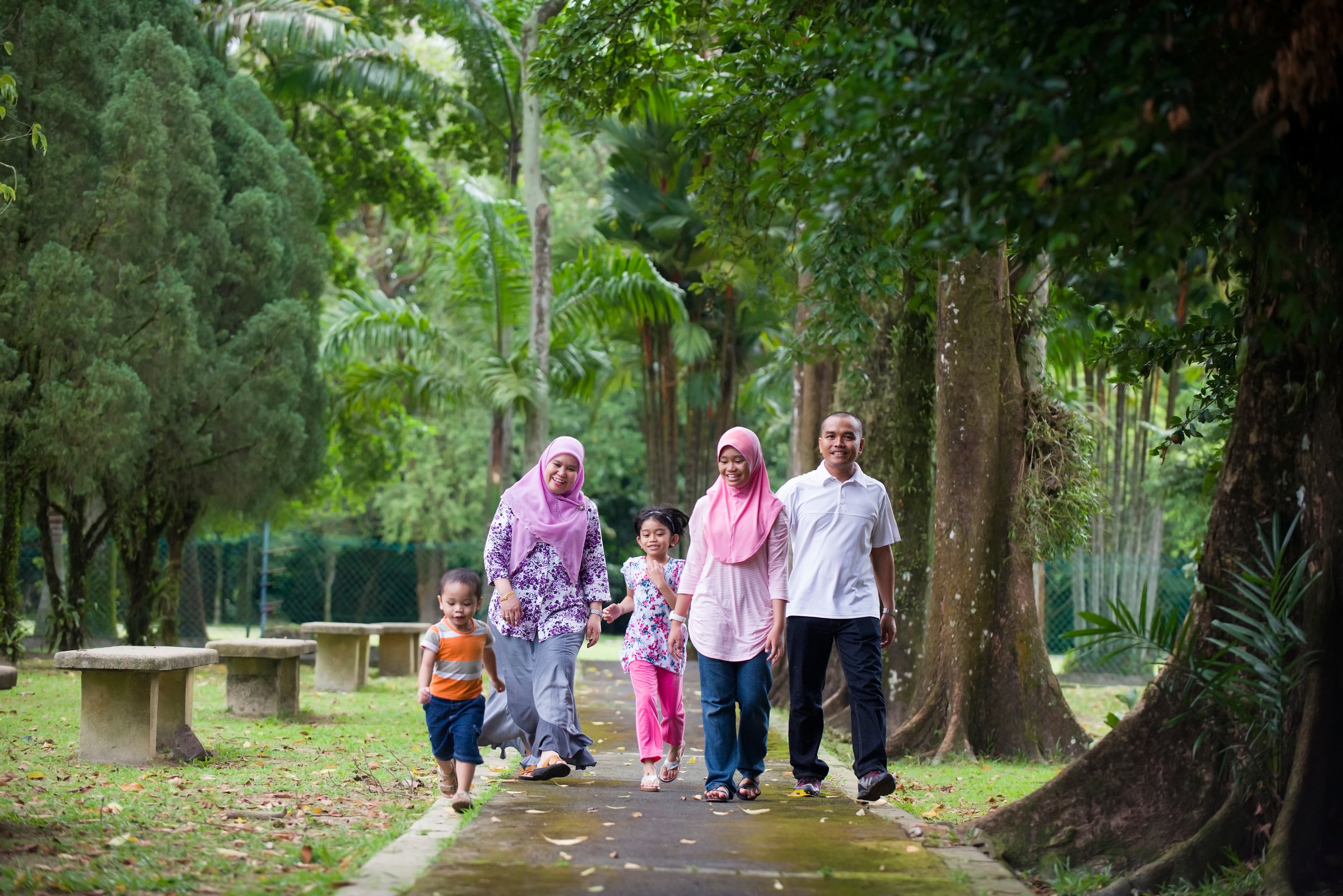 A family enjoying a walk together in a leafy park.